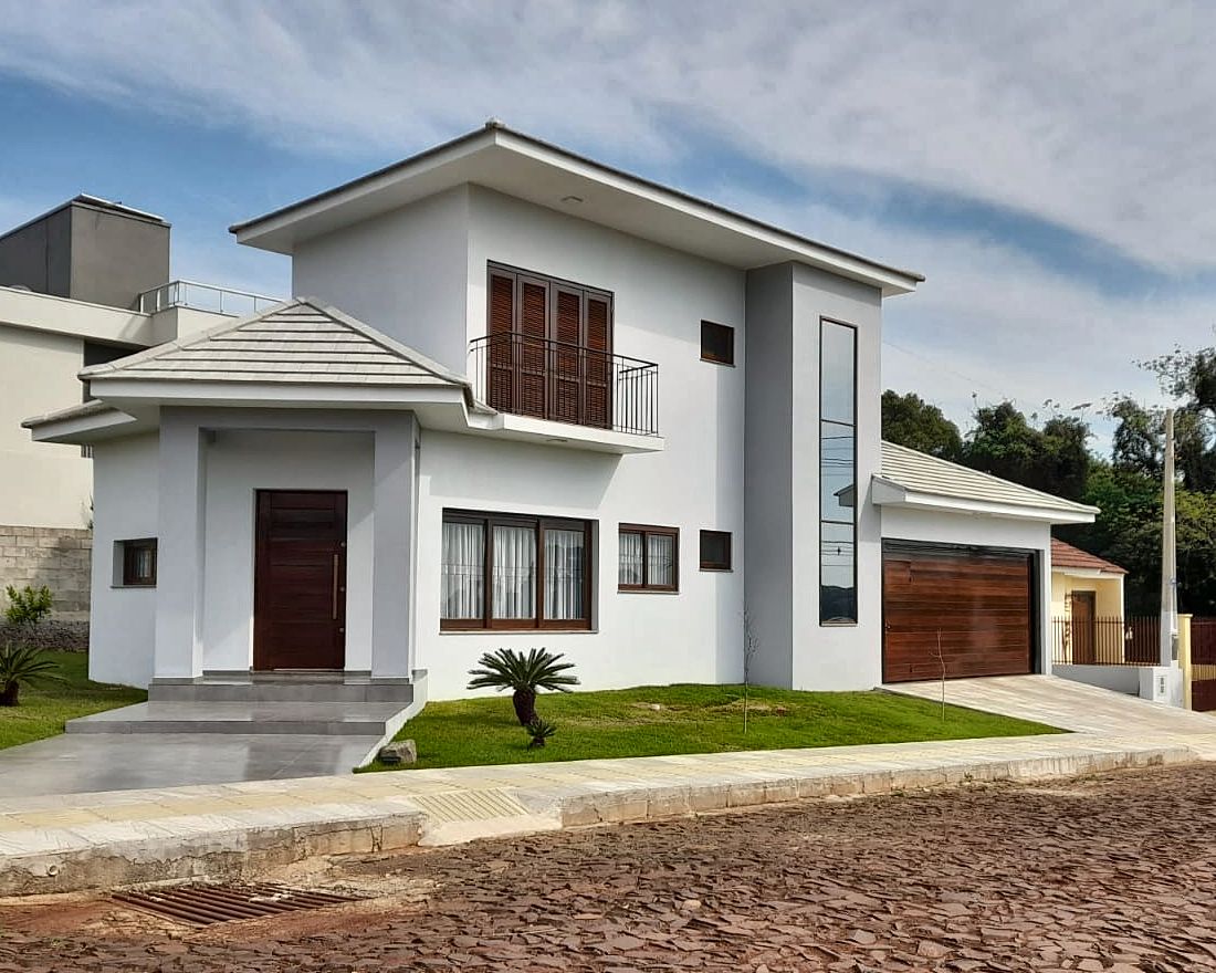 Casa de dois andares com porta pivotante, janelas, venezianas e portão de garagem em madeira feitos pela Esquadrias Sonnenberg