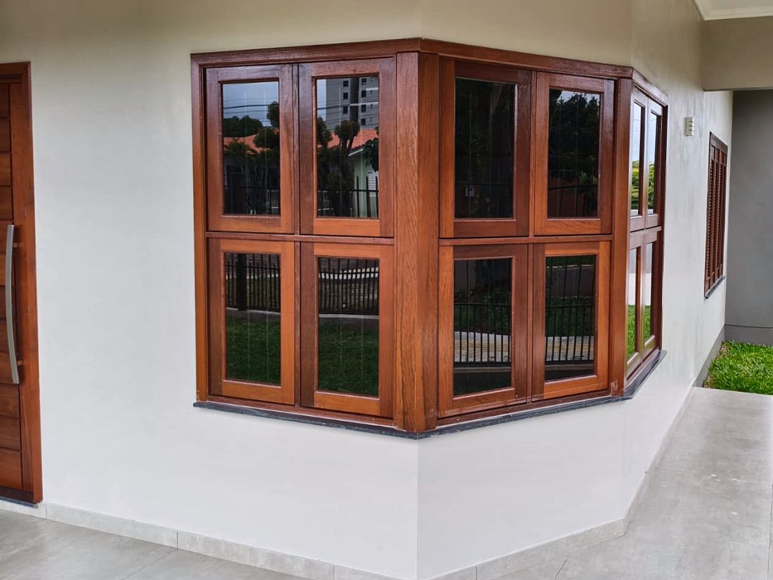Varanda com janela de canto de madeira e porta pivotante feitas pela Esquadrias Sonnenberg